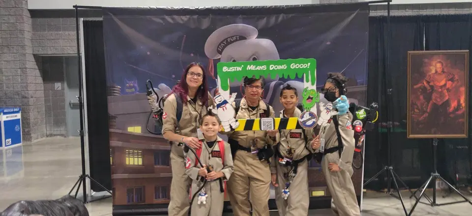 Ghostbusters Virginia members at a family event with kids and a Bustin Means Doing Good sign