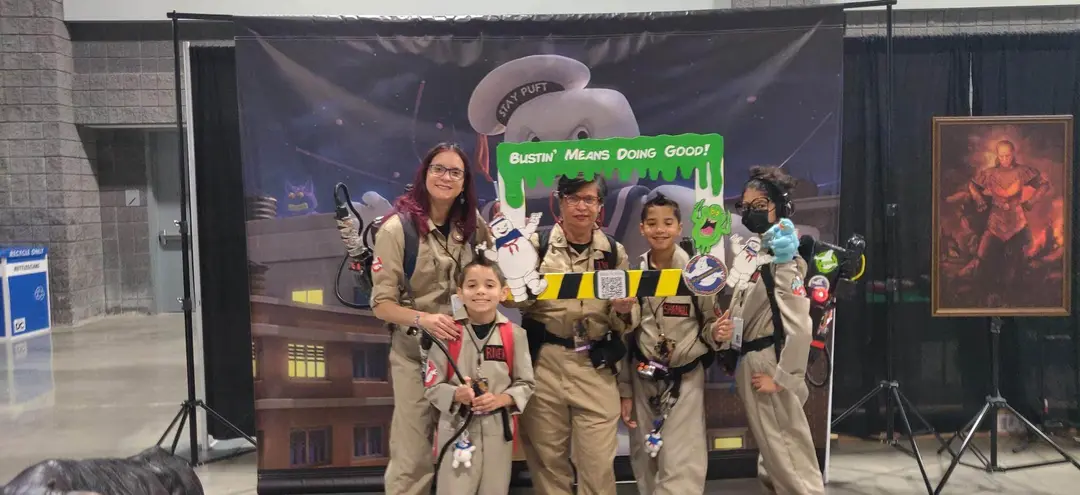 Ghostbusters Virginia members at a family event with kids and a Bustin Means Doing Good sign