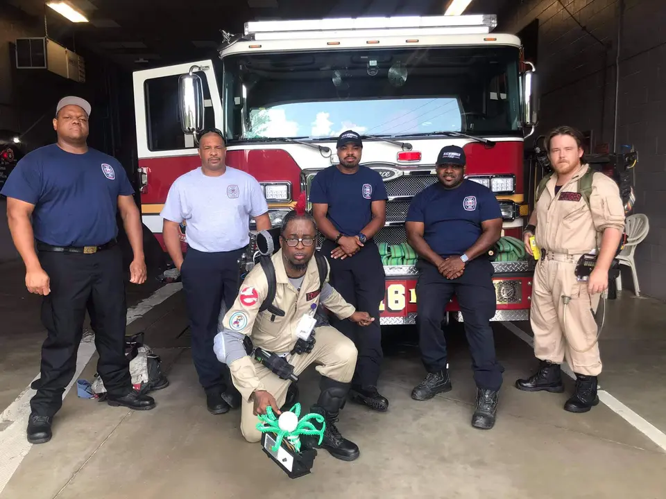 Ghostbusters Virginia member posing with firefighters in front of a fire truck