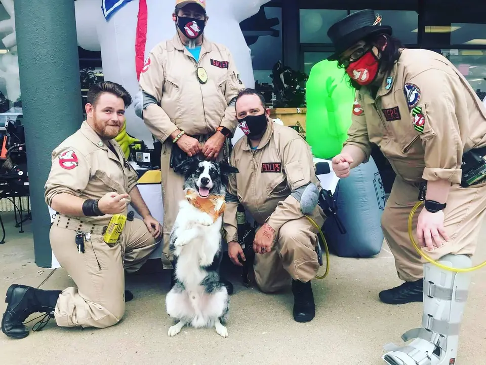 Ghostbusters Virginia members posing with a Slimer ghost puppet and a border collie dog