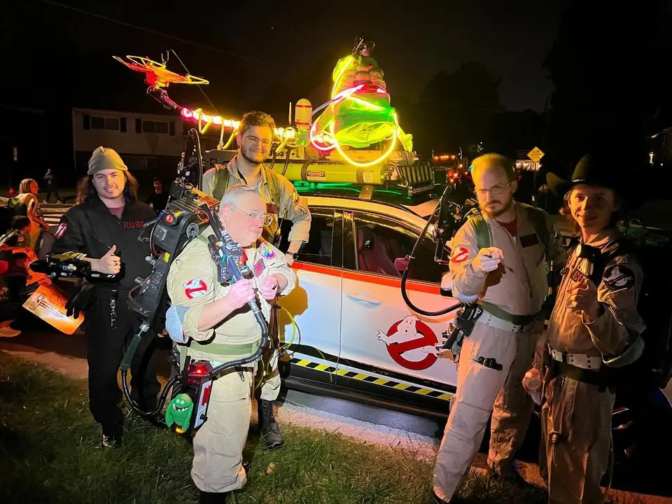 Ghostbusters Virginia member interacting with fans at a nighttime event next to the Ecto vehicle