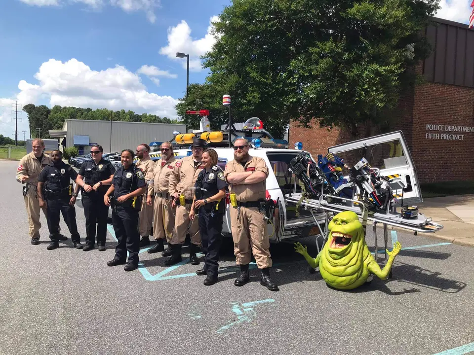 Ghostbusters Virginia members in full gear posing with local police officers and a Slimer prop